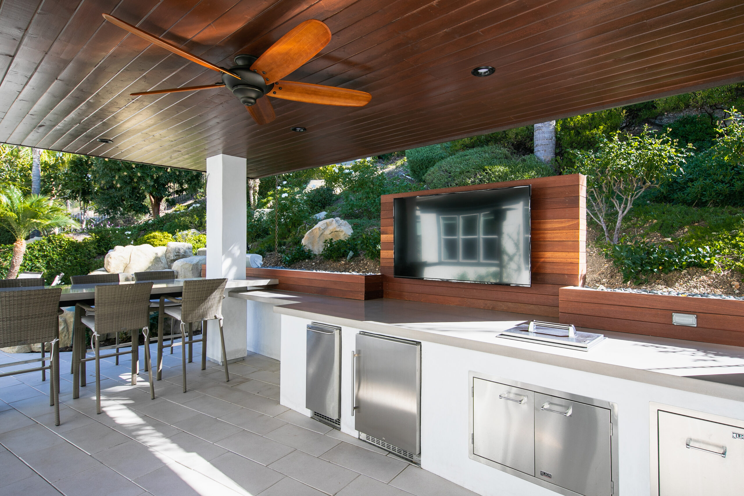 Custom outdoor kitchen under a covered cabana with dining area and outdoor entertainment space in Thousand Oaks, California.